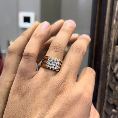 A man's hand holding a diamond ring with a solid gold band, featuring a clear diamond centerpiece.