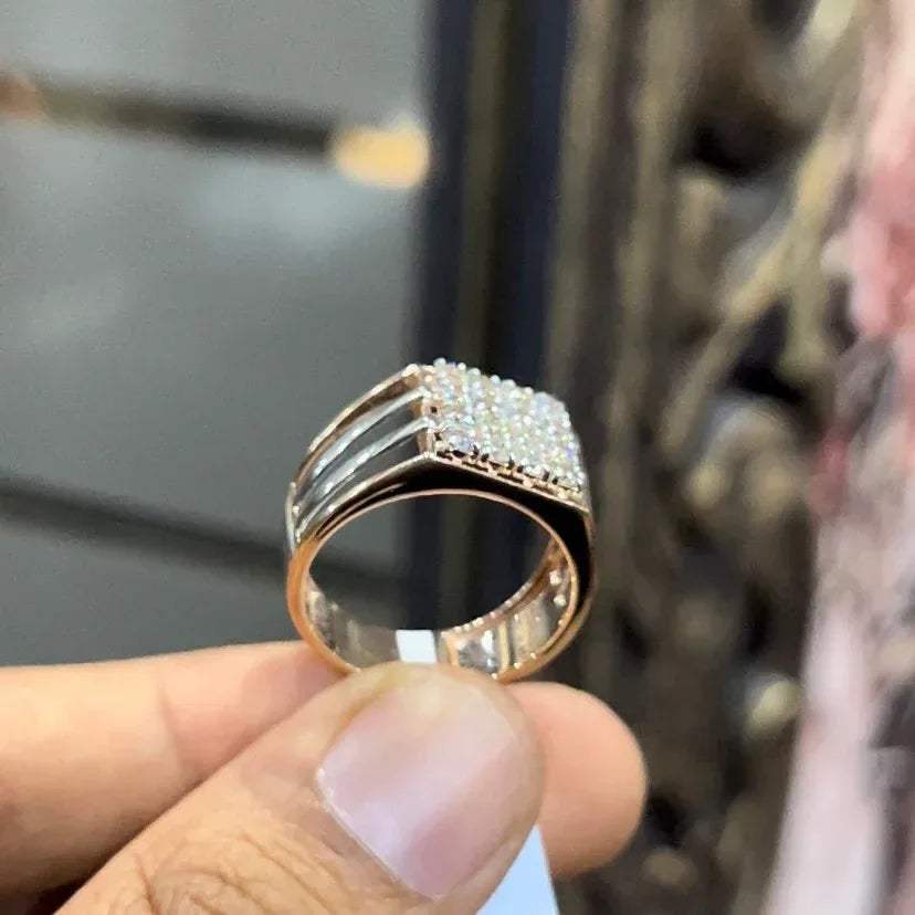 A man's hand holding a diamond ring with a solid gold band, featuring a clear diamond centerpiece.