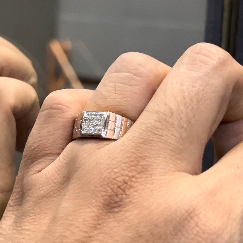 Stylish men’s diamond ring with a geometric square cluster centerpiece and textured rose gold band, shown in hand for scale.