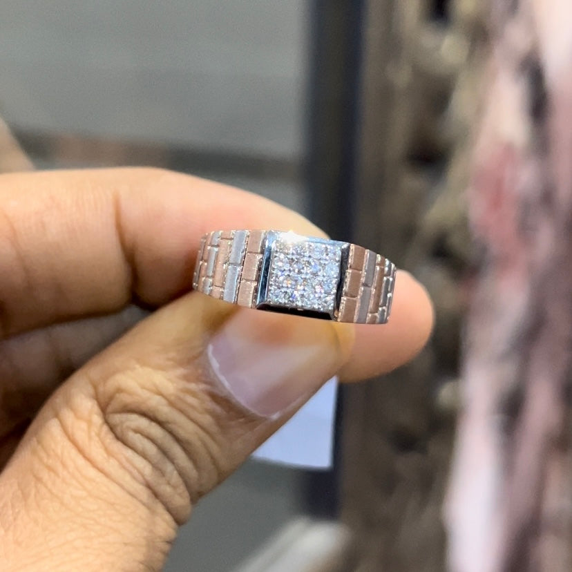 Stylish men’s diamond ring with a geometric square cluster centerpiece and textured rose gold band, shown in hand for scale.