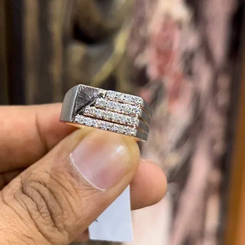 A man's hand displaying a diamond ring with a gold band. The ring has a polished finish with smaller diamonds.