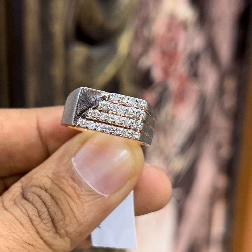 A man's hand displaying a diamond ring with a gold band. The ring has a polished finish with smaller diamonds.