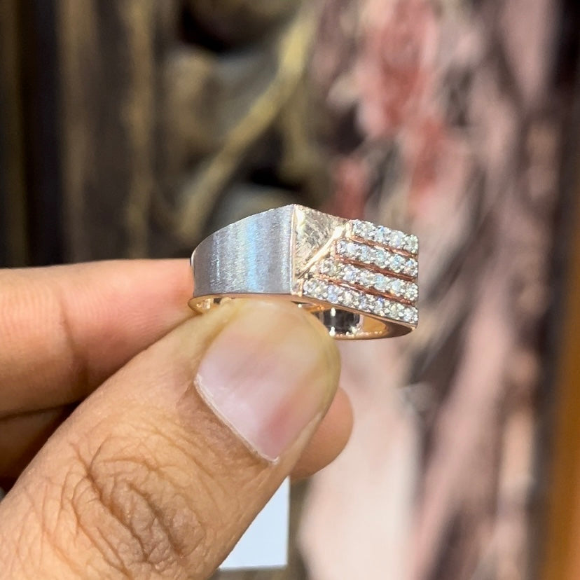 A man's hand displaying a diamond ring with a gold band. The ring has a polished finish with smaller diamonds.