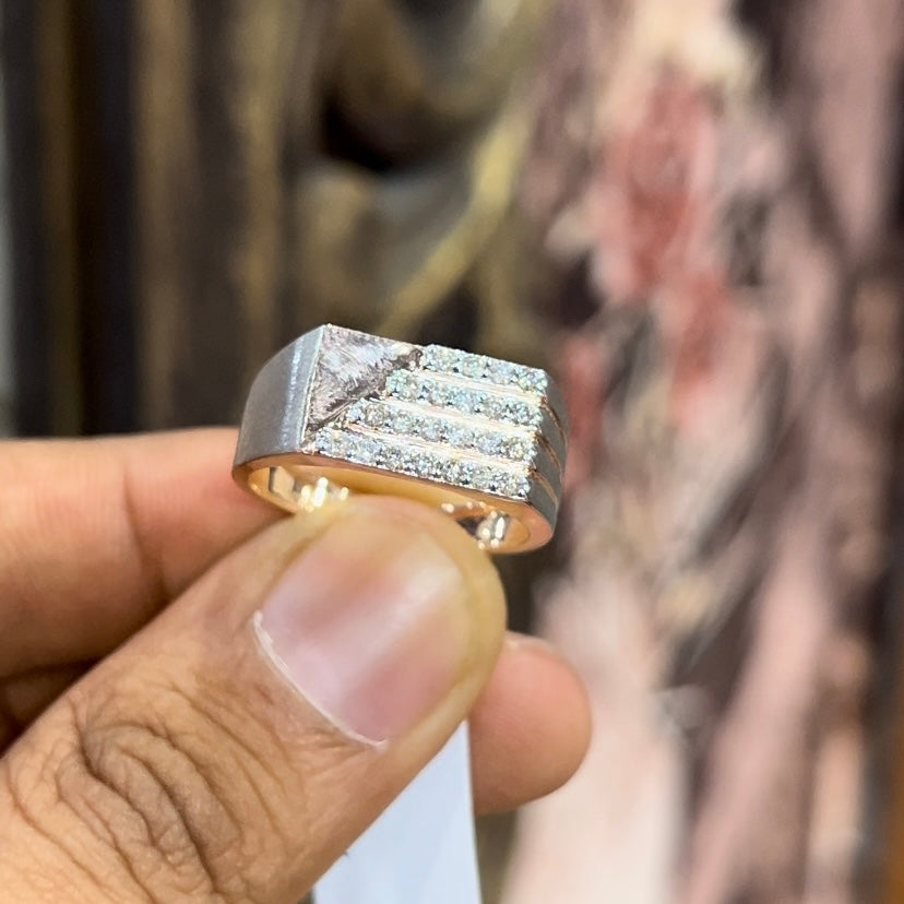 A man's hand displaying a diamond ring with a gold band. The ring has a polished finish with smaller diamonds.