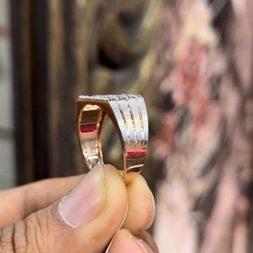 A man's hand displaying a diamond ring with a gold band. The ring has a polished finish with smaller diamonds.