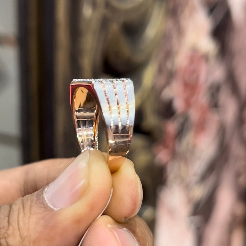 A man's hand displaying a diamond ring with a gold band. The ring has a polished finish with smaller diamonds.