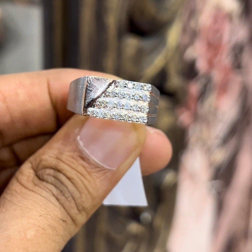 A man's hand displaying a diamond ring with a gold band. The ring has a polished finish with smaller diamonds.