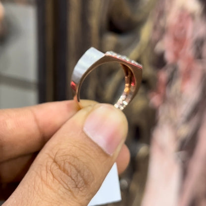 A man's hand displaying a diamond ring with a gold band. The ring has a polished finish with smaller diamonds.
