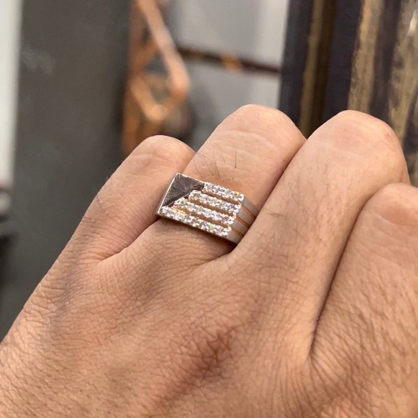 A man's hand displaying a diamond ring with a gold band. The ring has a polished finish with smaller diamonds.