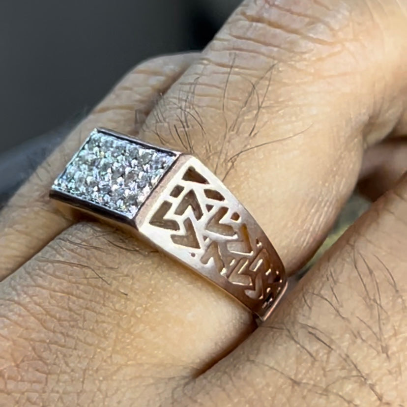 A man's hand displaying a diamond ring with a gold band. The ring has a polished finish with smaller diamonds.