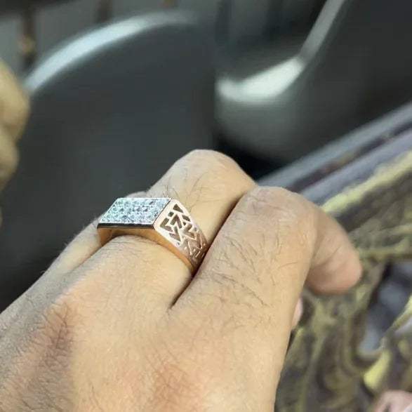 A man's hand displaying a diamond ring with a gold band. The ring has a polished finish with smaller diamonds.