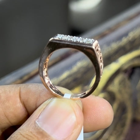 A man's hand displaying a diamond ring with a gold band. The ring has a polished finish with smaller diamonds.