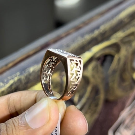 A man's hand displaying a diamond ring with a gold band. The ring has a polished finish with smaller diamonds.