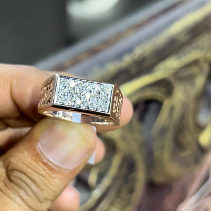 A man's hand displaying a diamond ring with a gold band. The ring has a polished finish with smaller diamonds.