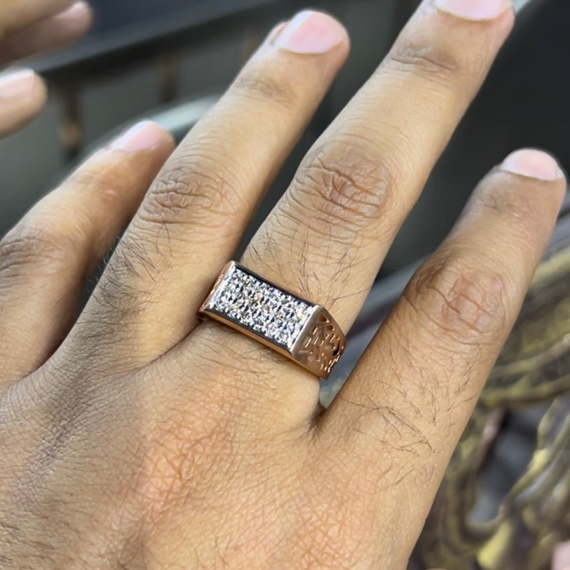 A man's hand displaying a diamond ring with a gold band. The ring has a polished finish with smaller diamonds.