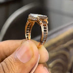 A man's hand holding a diamond ring with a solid gold band, featuring a prominent smaller diamonds along the band.