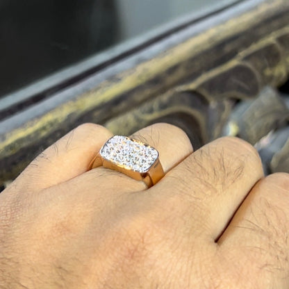 A man's hand holding a pave set diamond ring with a solid gold band, featuring a prominent smaller diamonds along the band.