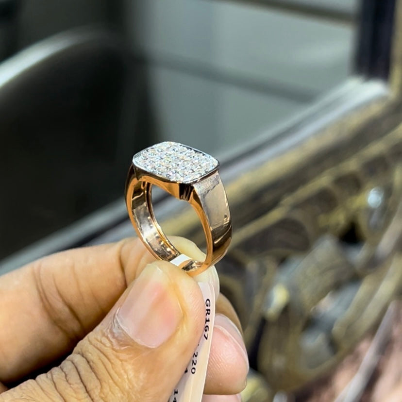 A man's hand holding a pave set diamond ring with a solid gold band, featuring a prominent smaller diamonds along the band.