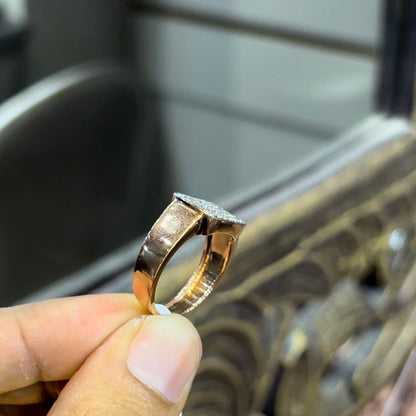 A man's hand holding a pave set diamond ring with a solid gold band, featuring a prominent smaller diamonds along the band.
