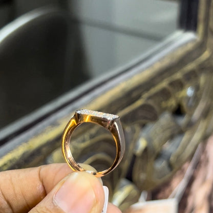 A man's hand holding a pave set diamond ring with a solid gold band, featuring a prominent smaller diamonds along the band.