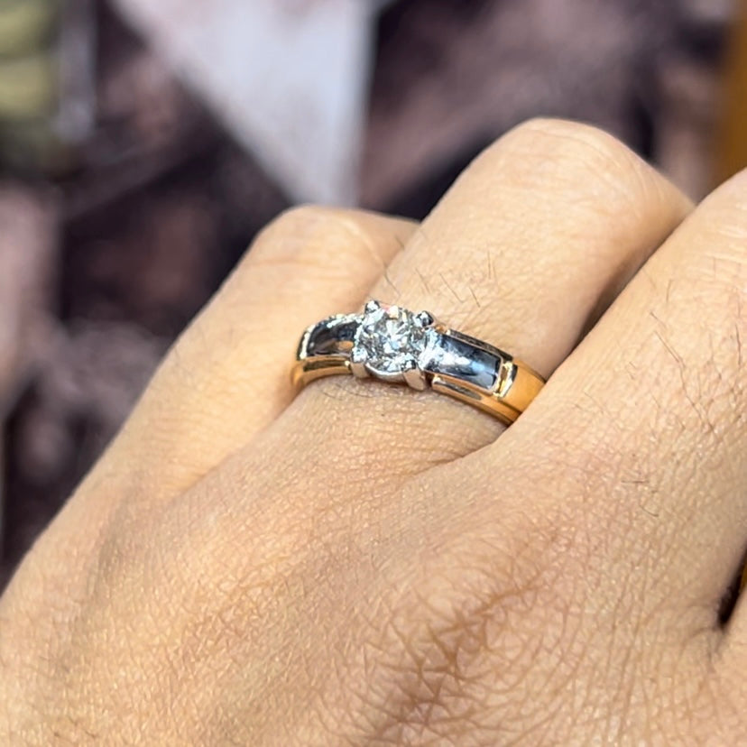 A man's hand holding a diamond solitaire ring with a gold ring.
