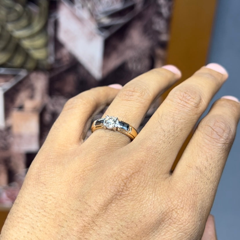 A man's hand holding a diamond solitaire ring with a gold ring.
