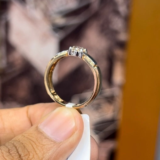 A man's hand holding a diamond solitaire ring with a gold ring.