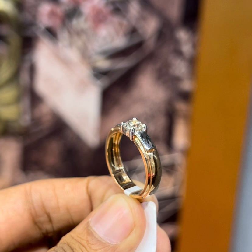 A man's hand holding a diamond solitaire ring with a gold ring.