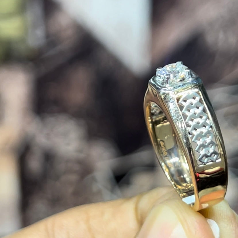 gold men's diamond ring with square solitaire and intricate lattice band detail shown on finger.