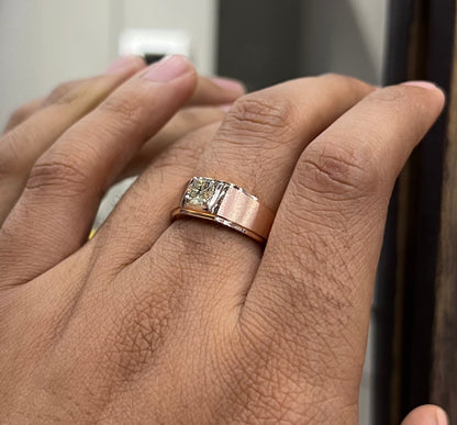 A man's hand displaying a solitaire men's diamond ring with a gold band.