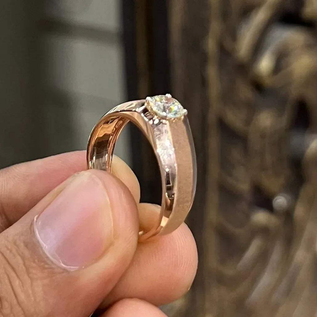 A man's hand displaying a gold band ring with a large, genuine diamond centerpiece.