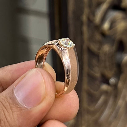 A man's hand displaying a gold band ring with a large, genuine diamond centerpiece.