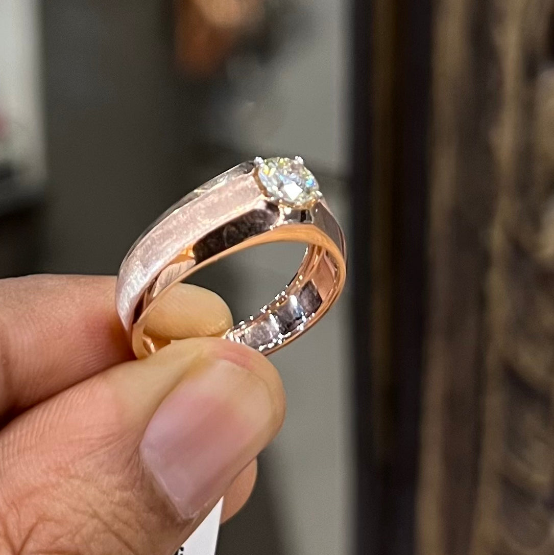 A man's hand displaying a gold band ring with a large, genuine diamond centerpiece.