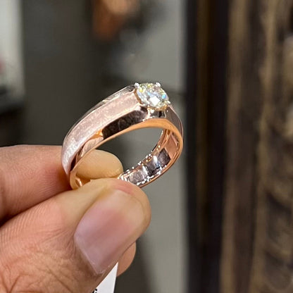 A man's hand displaying a gold band ring with a large, genuine diamond centerpiece.