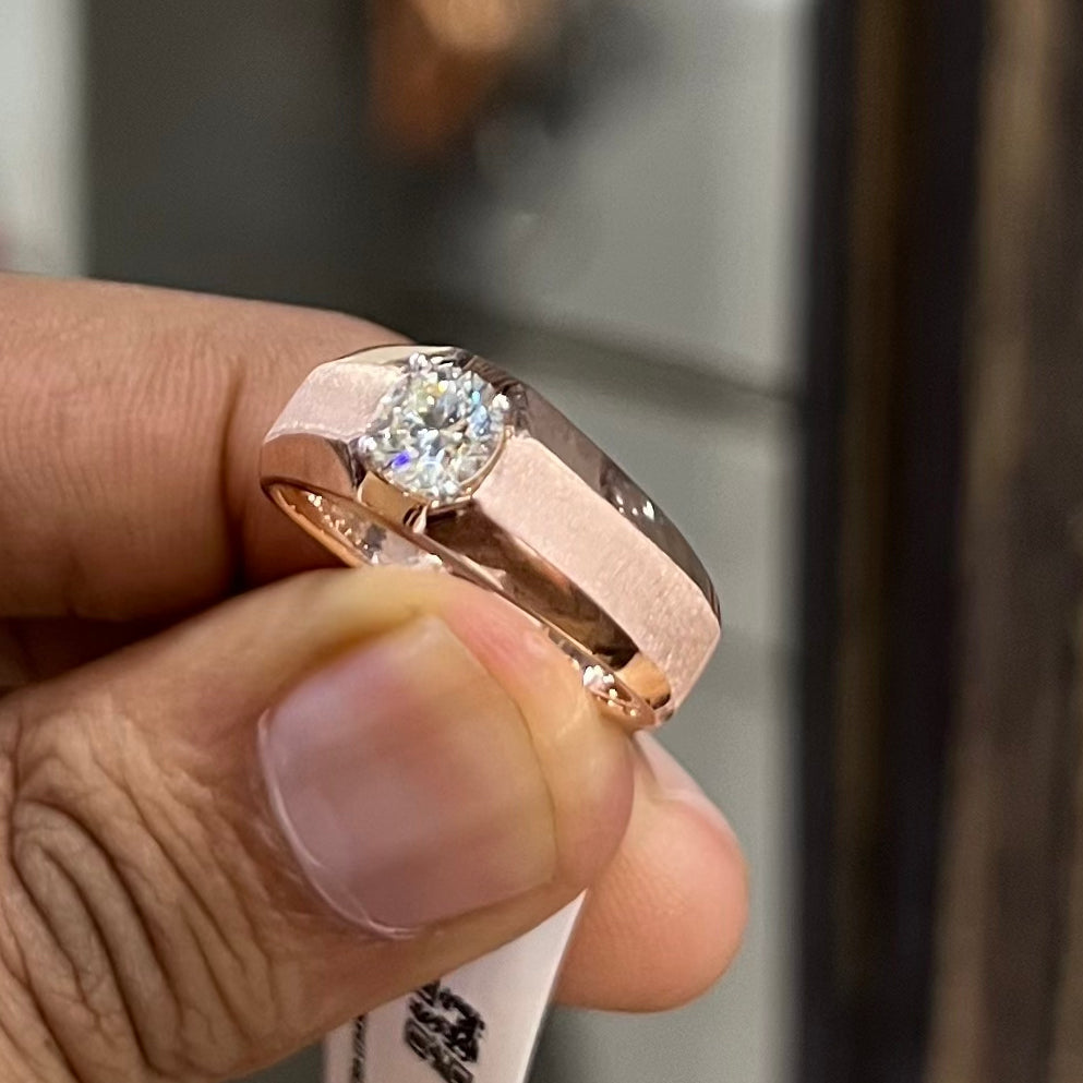 A man's hand displaying a gold band ring with a large, genuine diamond centerpiece.