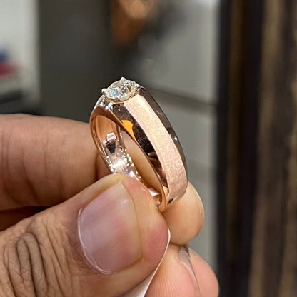 A man's hand displaying a gold band ring with a large, genuine diamond centerpiece.