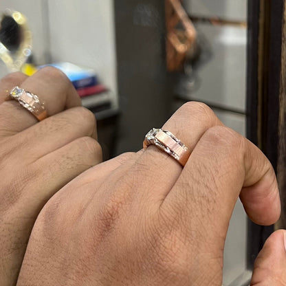 A man's hand holding a diamond solitaire ring with a gold band against a mirror.