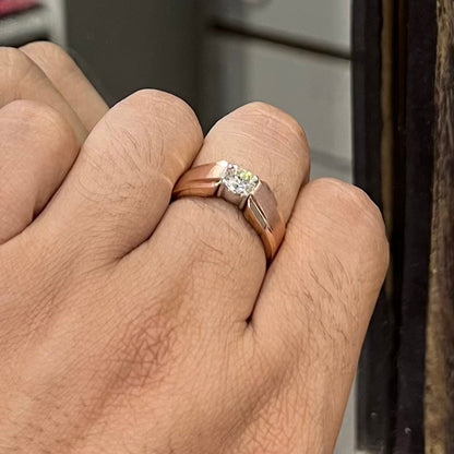 A man's hand holding a diamond solitaire ring with a gold band.