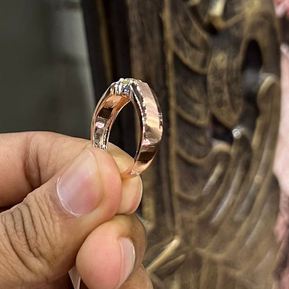 A man's hand holding a diamond solitaire ring with a gold band.