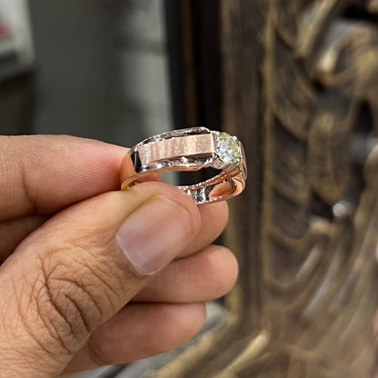 A man's hand holding a diamond solitaire ring with a gold band.