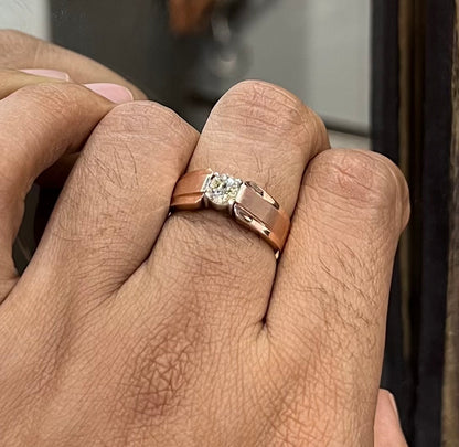 A man's hand holding a diamond solitaire ring with a gold band.