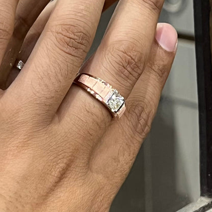 A man's hand displaying a gold band with a central genuine diamond solitaire ring.