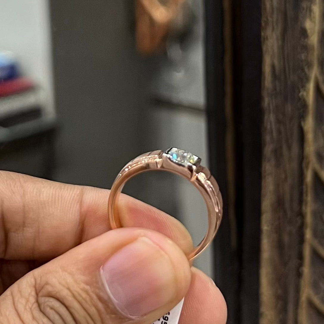 A man's hand displaying a gold band with a central genuine diamond solitaire ring.