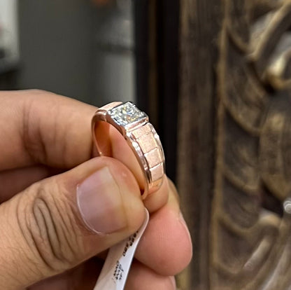 A man's hand displaying a gold band with a central genuine diamond solitaire ring.