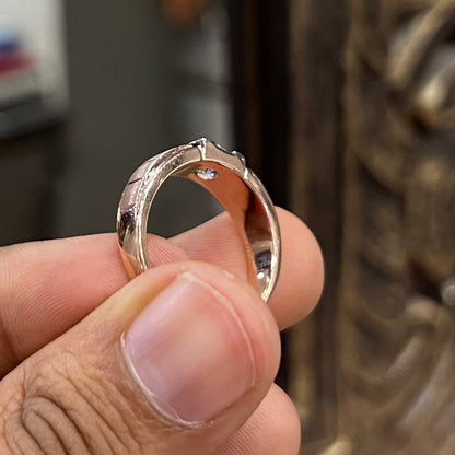 A man's hand displaying a gold band with a central genuine diamond solitaire ring.