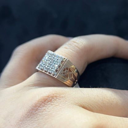 A man's hand displaying a gold band ring with smaller round cut diamonds.