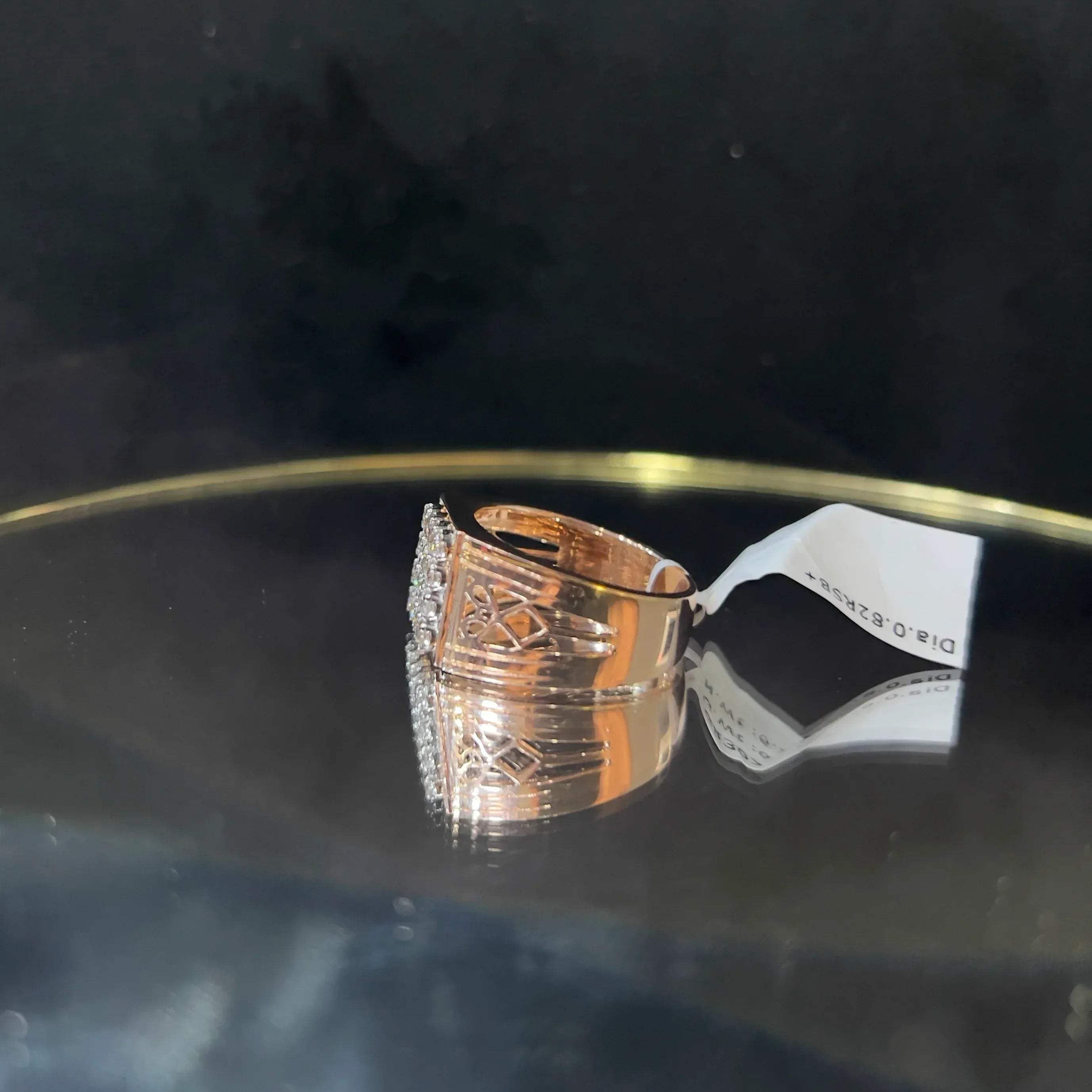 A gold band ring with smaller round cut diamonds is displaying on a reflective surface.