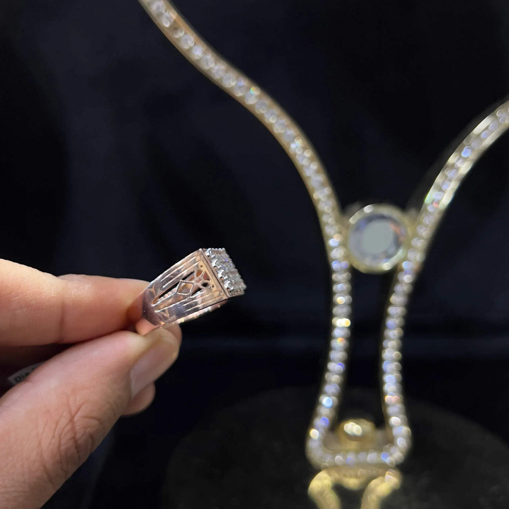 A man's hand displaying a gold band ring with smaller round cut diamonds.