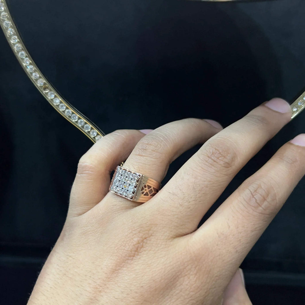 A man's hand displaying a gold band ring with smaller round cut diamonds.