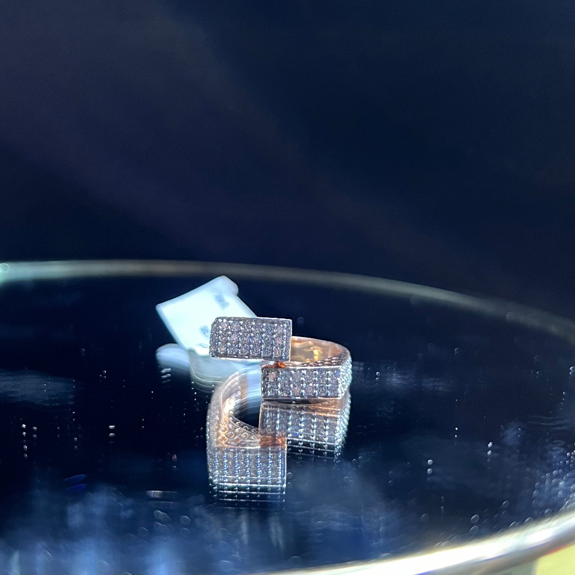 A man's hand displaying a 14K gold diamond ring with a solid band and a small diamond inlay on the top surface.